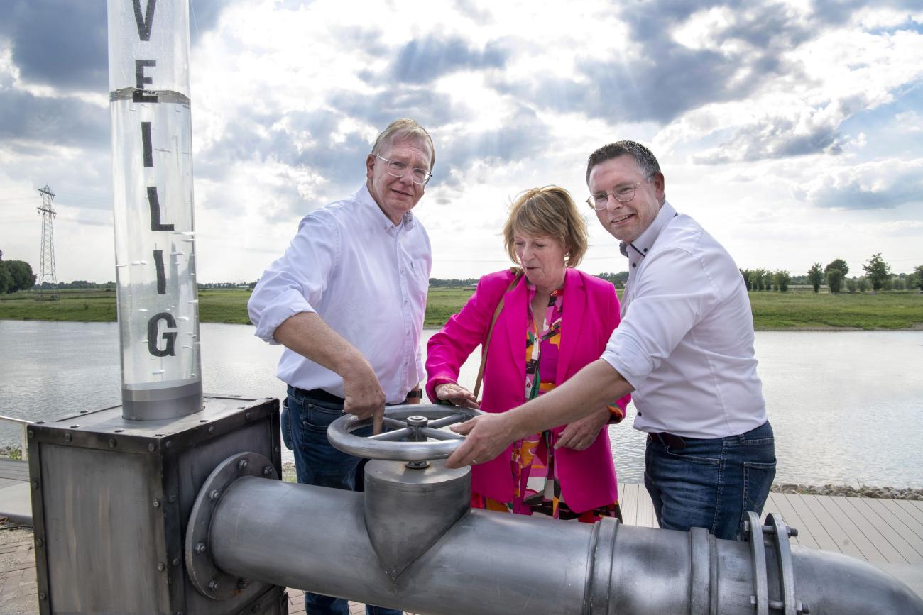 Jeroen Achten (dagelijks bestuurder van Waterschap Limburg), Gijs Ploegmakers (directeur van Ploegam) en wethouder Marij Pollux draaien de kraan open bij de opening van de zelfsluitende waterkering in Steyl.