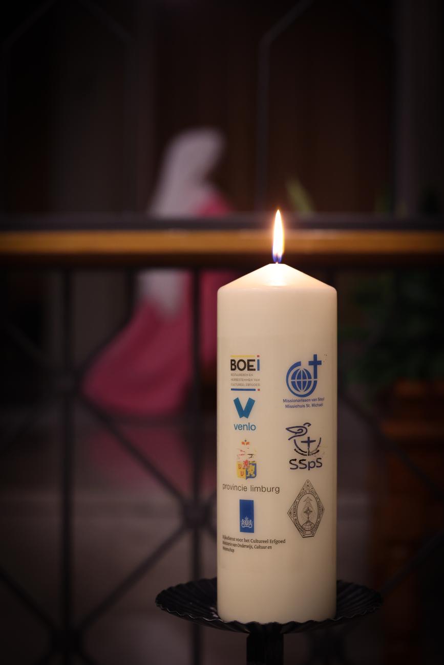 Brandende kaars met roze zuster op de achtergrond
