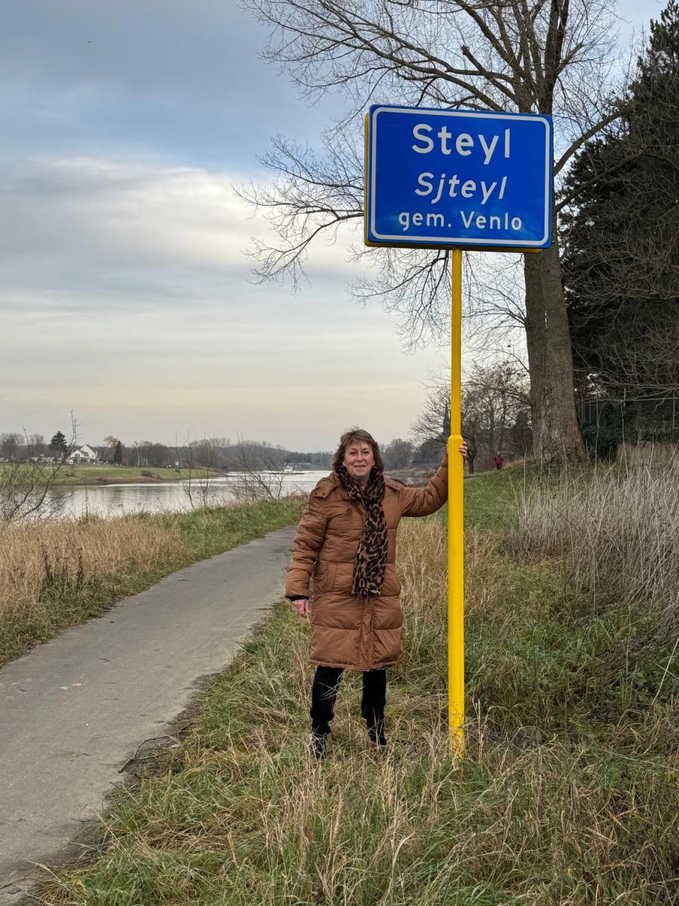 Wethouder Pollux bij plaatsnaambord van Belfeld