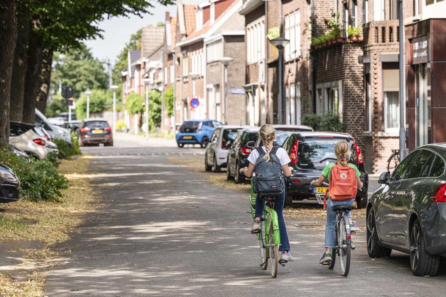 Twee fietsende kinderen op straat.