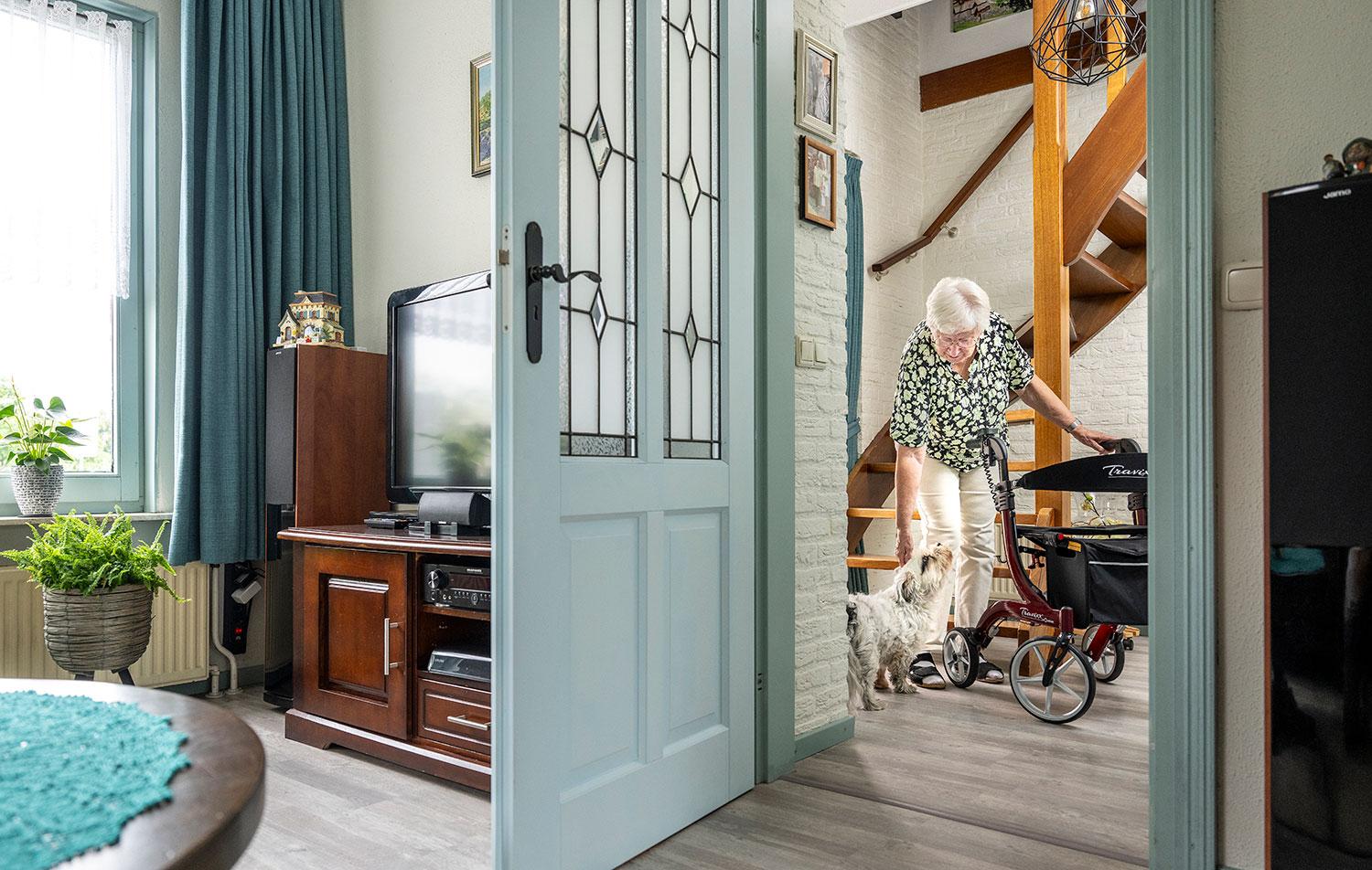 Vrouw in hal met hondje en rollator