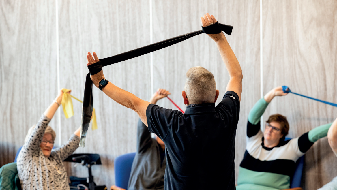 Sportende ouderen in een gymzaal die bezig zijn met een sport-elastiek
