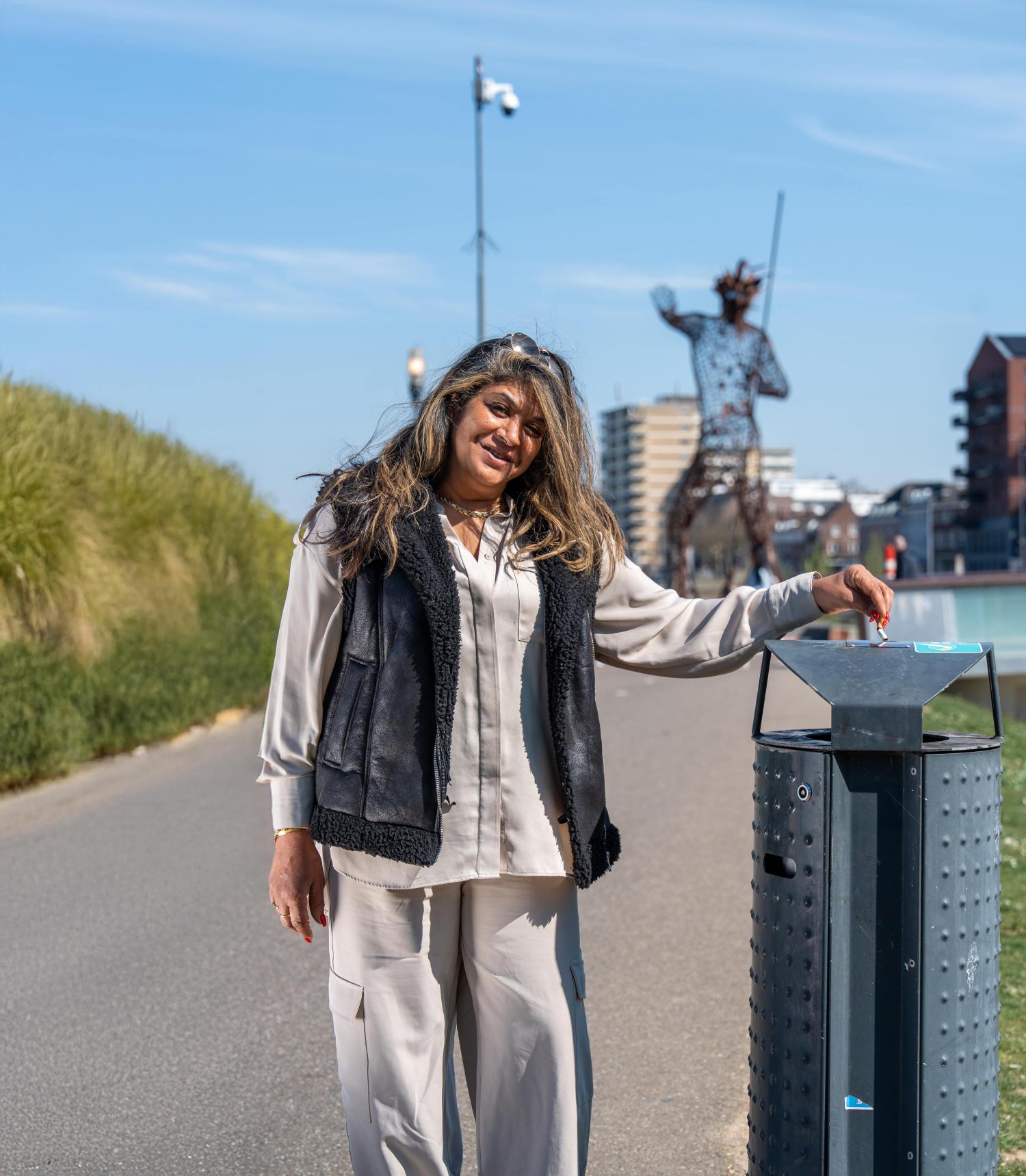 Een inwoner die op de Maasboulevard in Venlo bij een afvalbak staat en daarop een sigarettenpeuk uitdrukt.