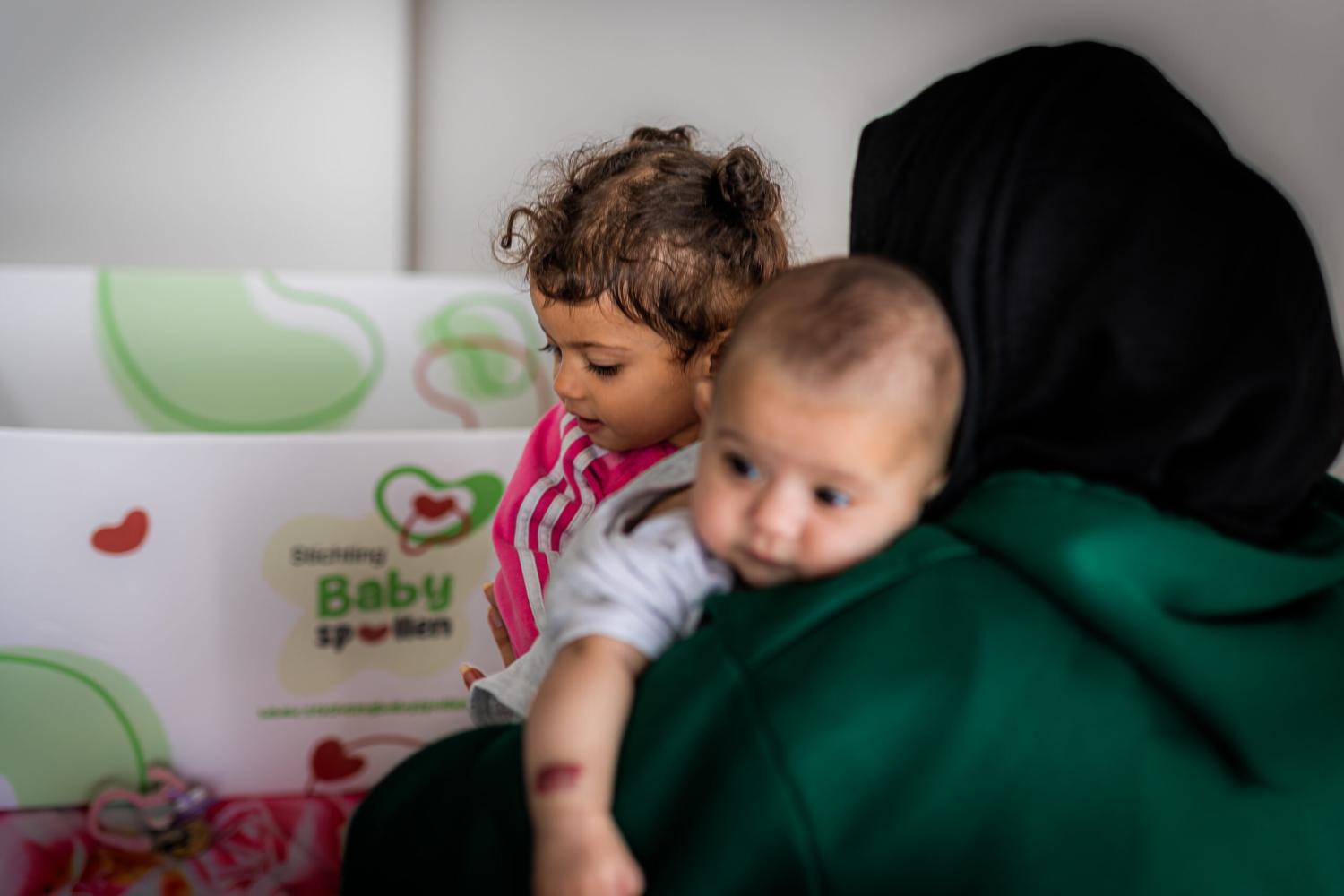 moeder met twee kinderen en de baby spullen box
