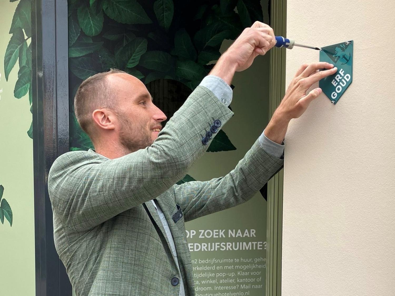 Wethouder Tom Verhaegh monteert Erfgoudschild aan pand met monumentenstatus in Venlo