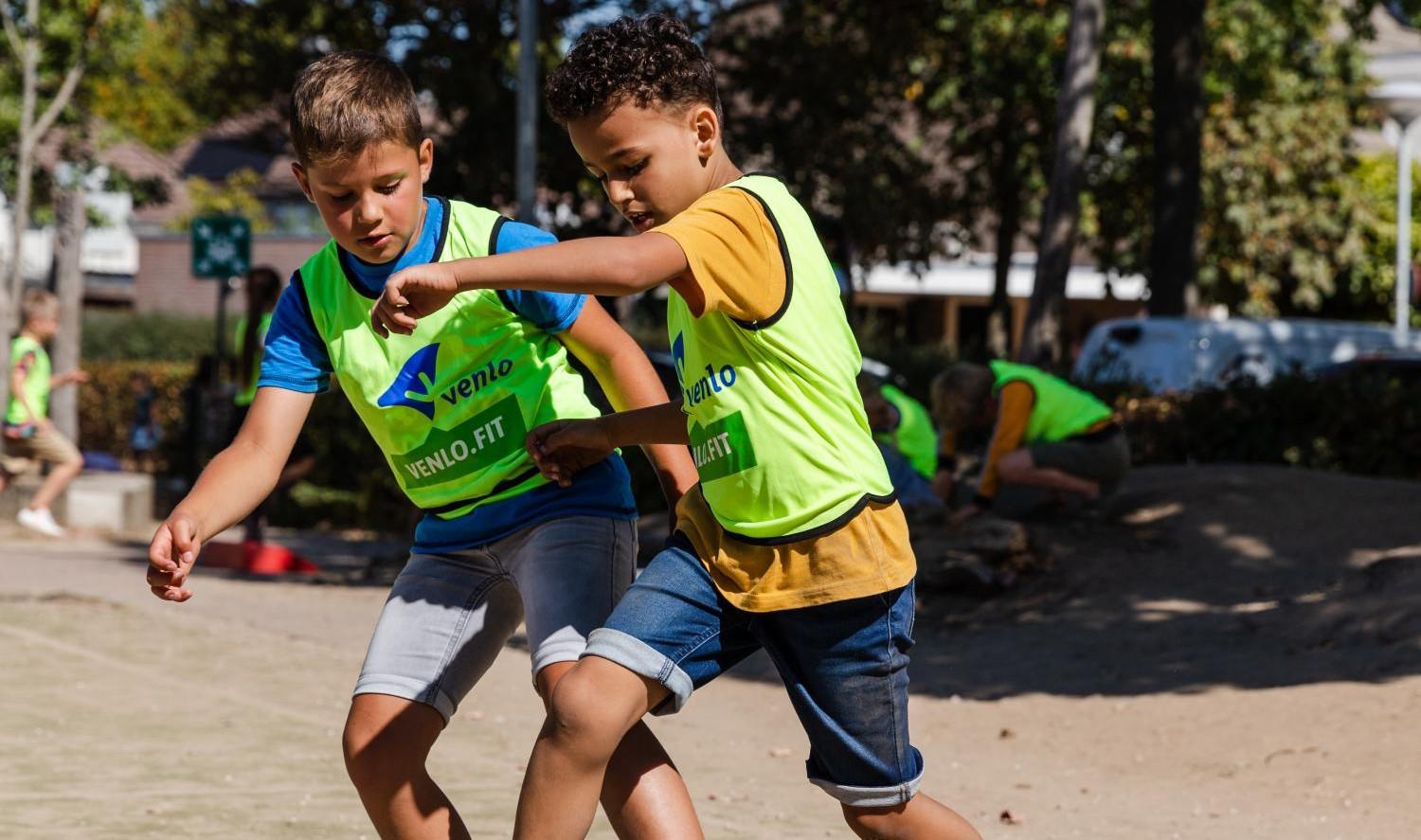 Voetballende kinderen buiten op het schoolplein 
