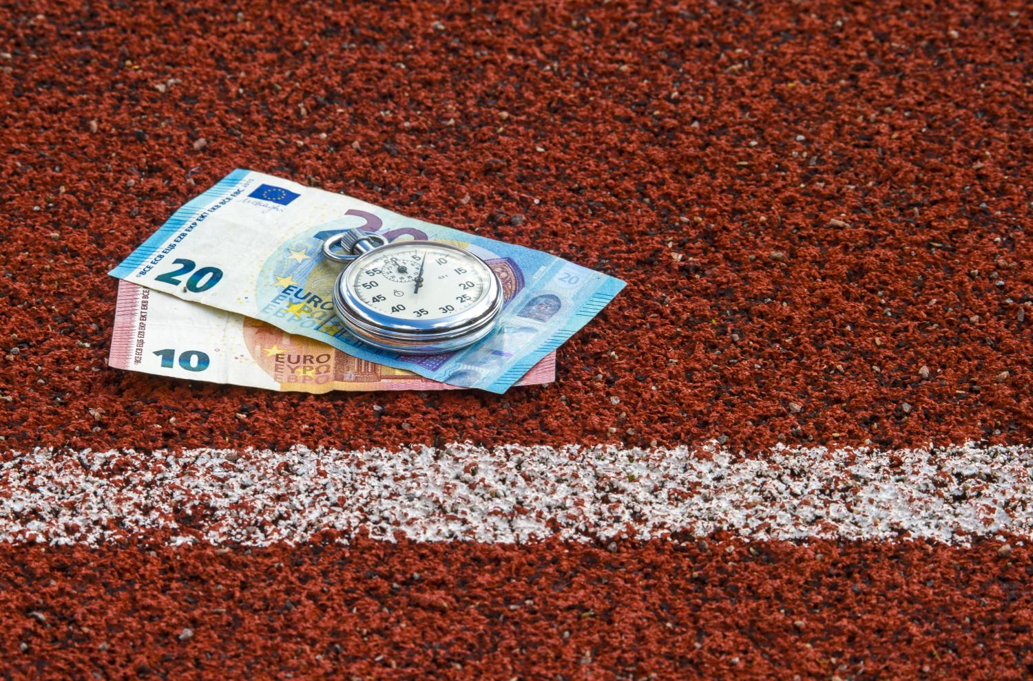 Geld en een stopwatch dat ligt op een sportbaan