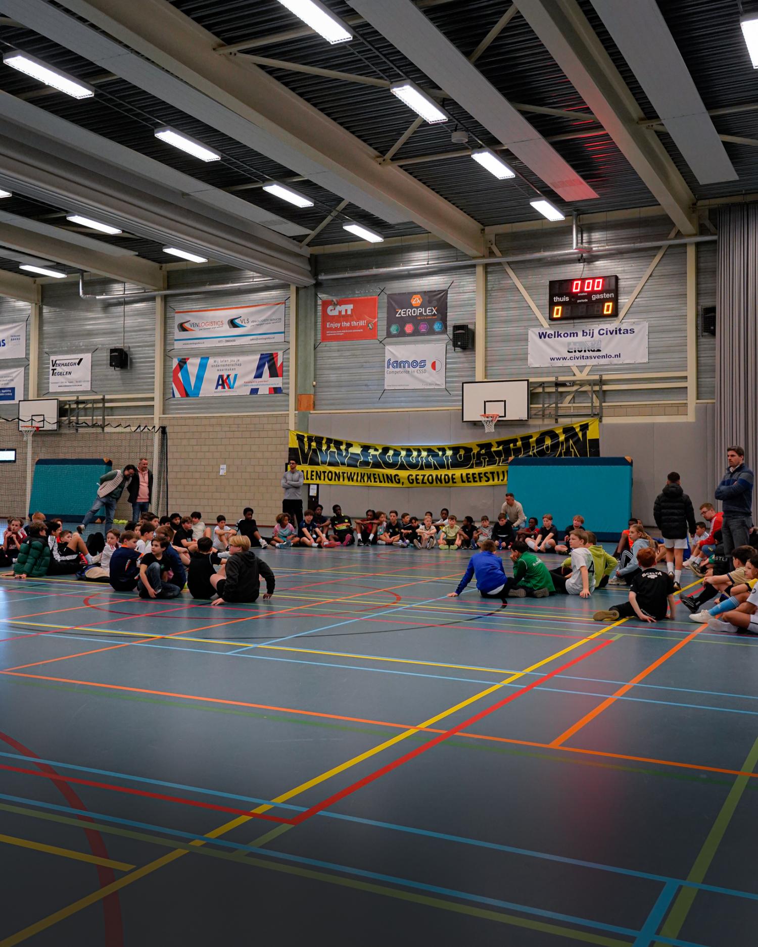 Een gymzaal met kinderen die op de grond zitten