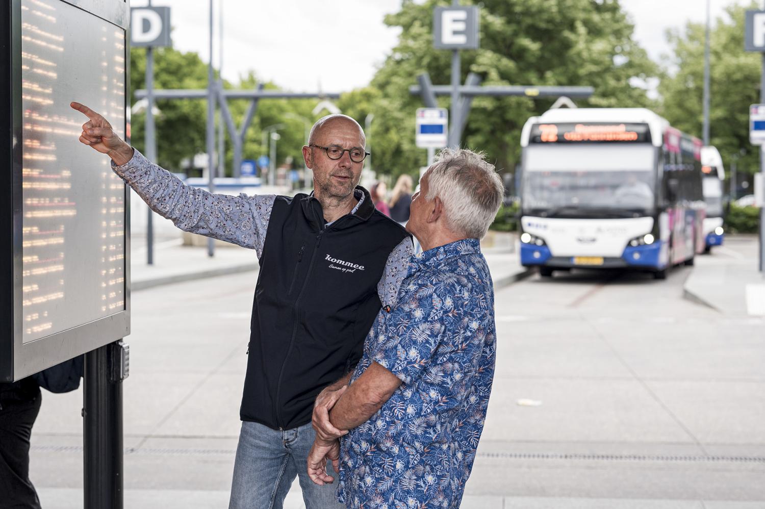 Meneer die aan een oudere dame uitlegt hoe ze moet reizen met het openbaar vervoer