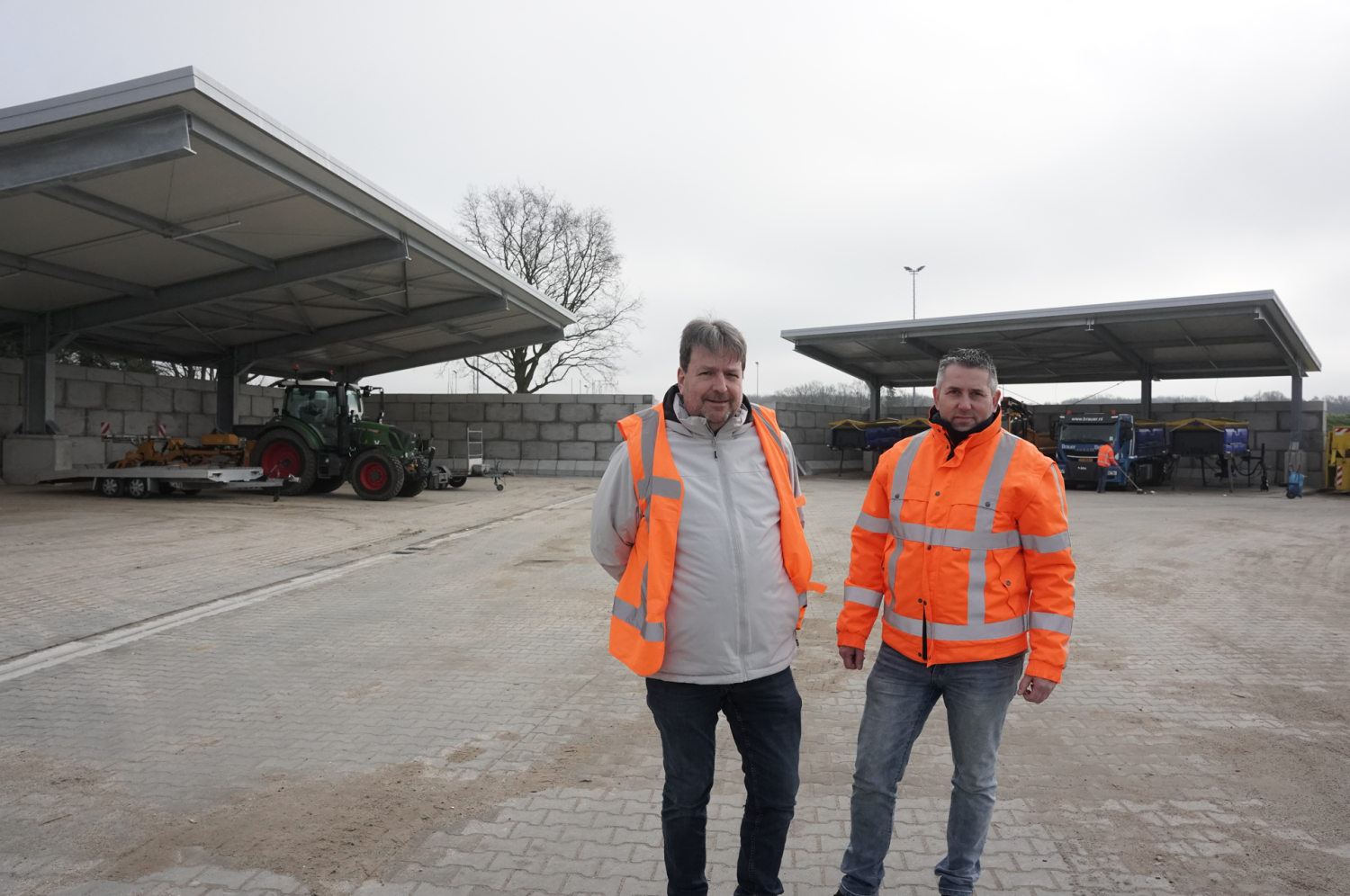 twee mannen met oranje hesjes op een opslag locatie van strooiwagens