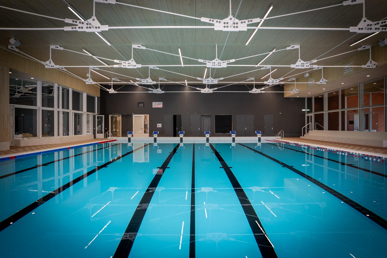 Het wedstrijdbad van zwembad De Ploens met meerdere zwembanen, startblokken en een moderne overdekte zwemhal.