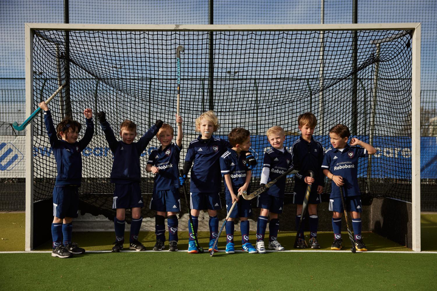 juigende kinderen in hockeykleding die samen in de goal staan
