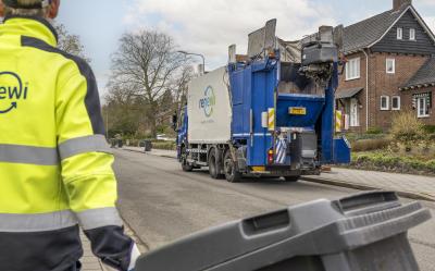 Iemand van Renewi die met een container in de hand naar de inzamelvrachtwagen loopt.