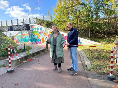 Inwoonster Debbie van Avesaath en stadsdeelmanager Richard Bosman openen samen de fietsdoorgang in de Vossener.