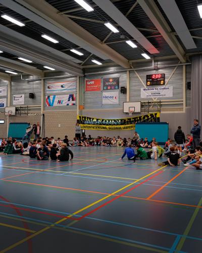 Een gymzaal met kinderen die op de grond zitten