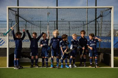 juigende kinderen in hockeykleding die samen in de goal staan