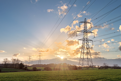 Meerdere stroommasten in een landschap met ondergaande zon